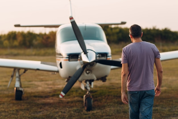 Pilot człowiek idący obok małego prywatnego samolotu.