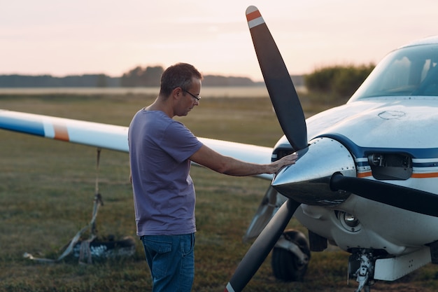 Pilot mężczyzna stojący obok małego prywatnego samolotu.