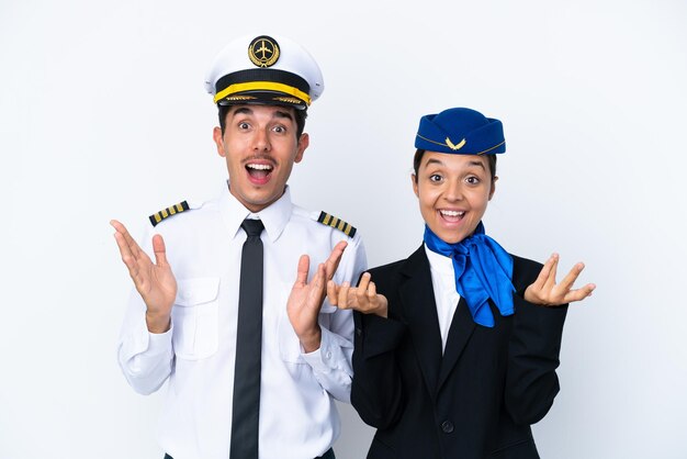 Pilot samolotu i stewardessa rasy mieszanej na białym tle z zaskoczeniem i zszokowanym wyrazem twarzy