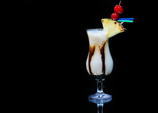 Zdjęcie pina colada, tropikalny napój z owocami i alkoholem na czarnym tle z odbiciem
