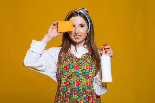 Zdjęcie pinup kobieta trzyma butelkę zupy do kurzu kobieta pinup z szczęśliwą twarzą na żółtym tle