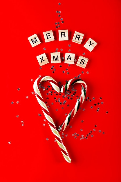 Zdjęcie pionowa kartka świąteczna na czerwonym tle lollipop trzcinowe gwiazdki i napis wesołych świąt w języku angielskim