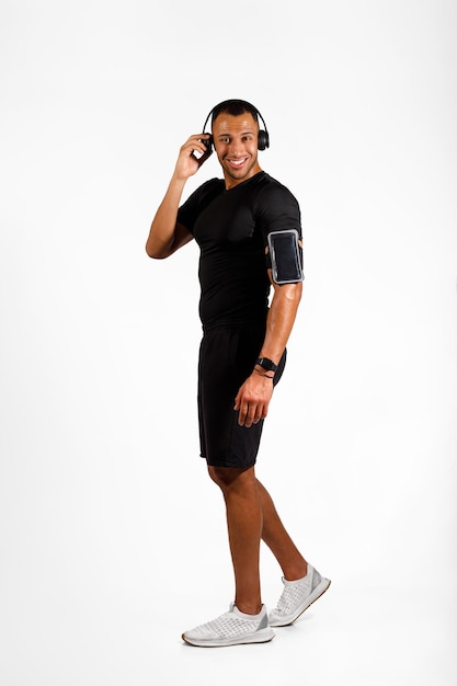 Pionowe ujęcie czarnego sportowca w słuchawkach na białym tle
