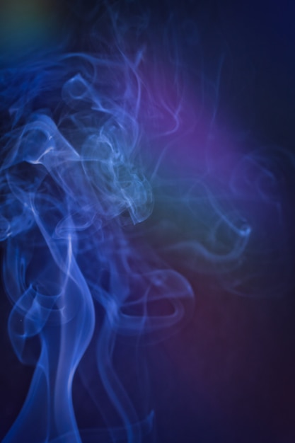 Pionowe ujęcie dymu w kolorowym podświetleniu z niebieską nutą