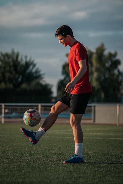 Zdjęcie pionowe ujęcie gracza dotykającego stopami boiska piłkarskiego.