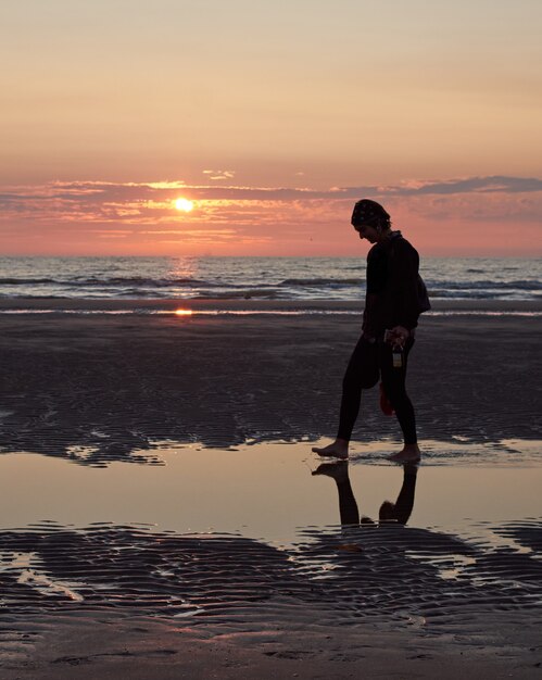 Pionowe ujęcie wesołej kaukaskiej kobiety z Hiszpanii cieszącej się zachodem słońca na plaży