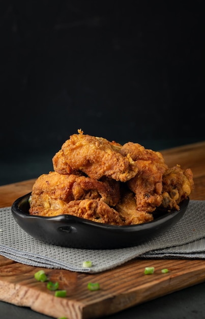 Pionowe zdjęcie talerza pysznego, chrupiącego, smażonego kurczaka na drewnianym stole