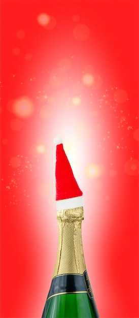 Pionowy baner Czerwony kapelusz Świętego Mikołaja na butelce szampana na świątecznym czerwonym tle świątecznym