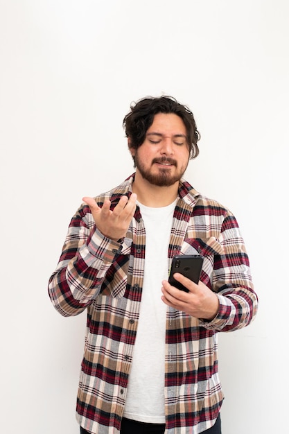 Pionowy obraz latynoskiego mężczyzny irytujący dla jego telefonu komórkowego na białym tle