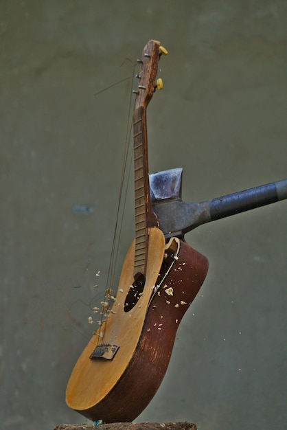 Pionowy obraz siekiery rozbijającej gitarę akustyczną