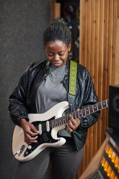 Pionowy Portret Czarnej Kobiety Grającej Na Gitarze Elektrycznej Podczas Komponowania Piosenki W Nagraniu