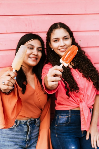 Pionowy portret przyjaciół łacińskich kobiet trzyma popsicle