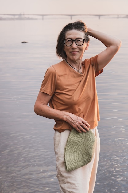 Pionowy portret szczęśliwej uśmiechniętej starszej azjatyckiej kobiety na tle morza