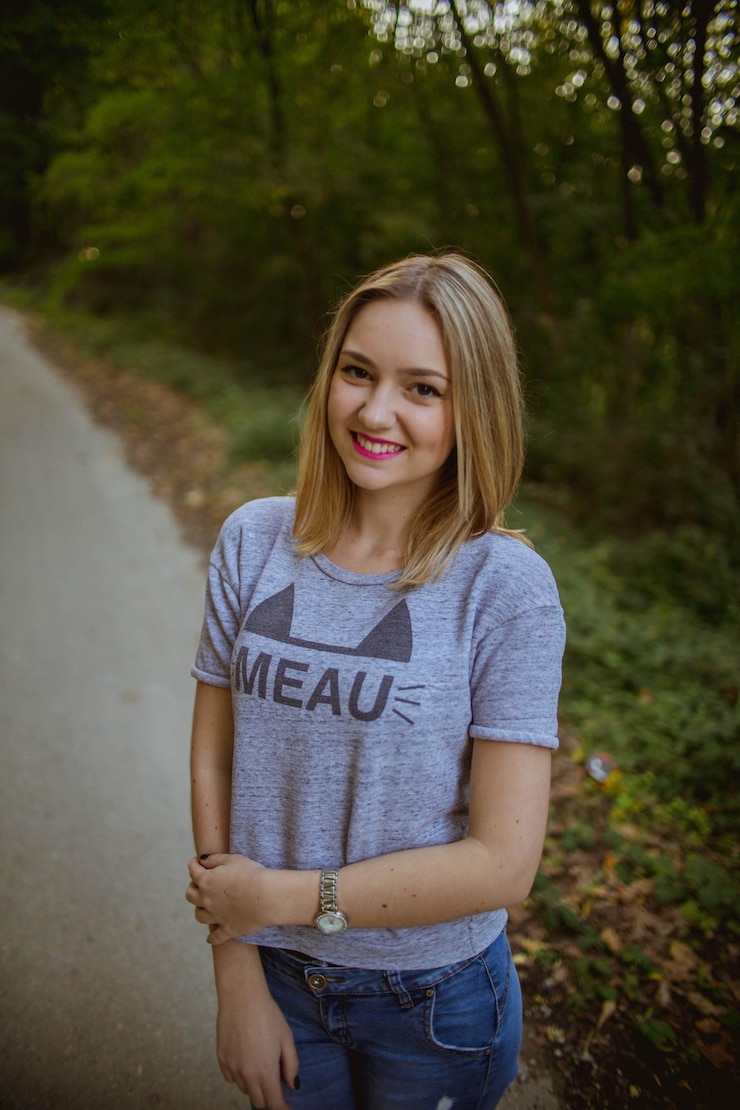 Zdjęcie pionowy zdjęcie młodej blondynki pozującej na drodze w pobliżu lasu