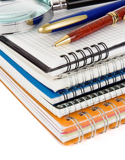 Pióro i ołówek na sprawdzonym notebooku na białym tle na białej powierzchni