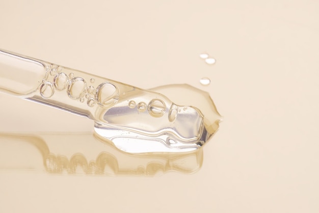 Zdjęcie pipeta z serumowym olejem żelowym lub innym produktem kosmetycznym na beżowym tle makro