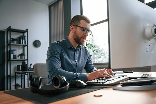 Pisanie na klawiaturze Mężczyzna w formalnym ubraniu pracuje w nowoczesnym biurze Przy użyciu komputera