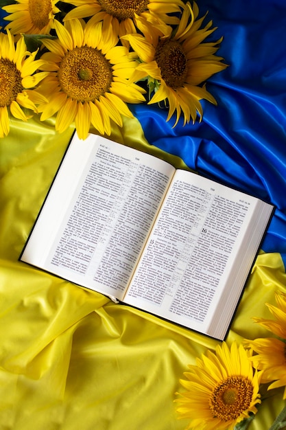 Zdjęcie pismo święte biblii i słoneczniki na tle flagi ukrainy