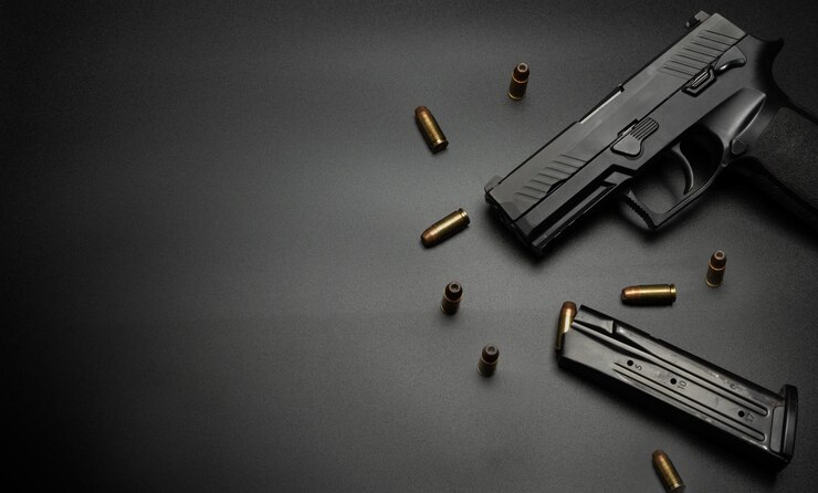 Pistolet jest umieszczony na czarnym tle z nabojami 9 mm dookoła Pomysł na broń dla ofiary