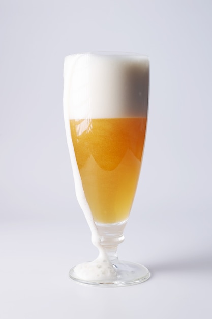 Piwo z pianką spływającą po krawędzi szklanego zbliżenia