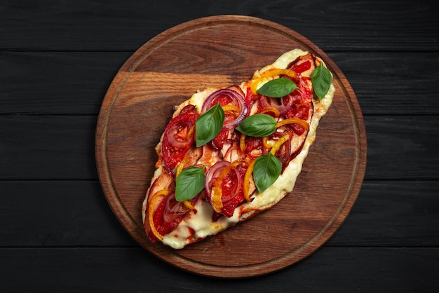 Pizza bezglutenowa pizza z widokiem z góry na płaskim chlebie z warzywami na czarnym drewnianym tle