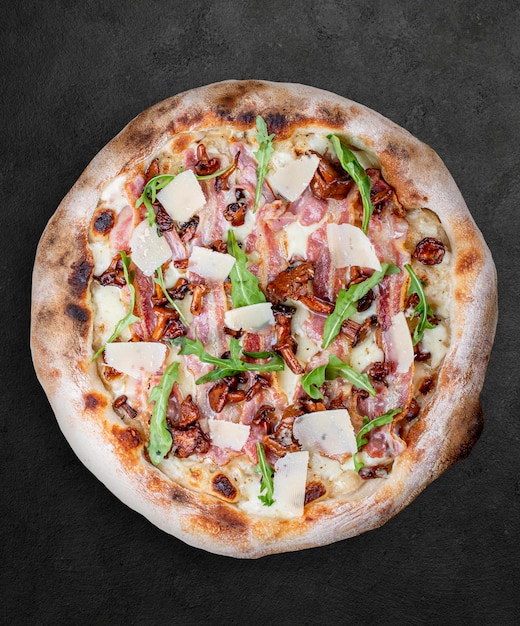 Pizza Carbonara z boczkiem kurki rukola mozzarella parmezan pesto neapolitańska okrągła pizza na ciemnym tle