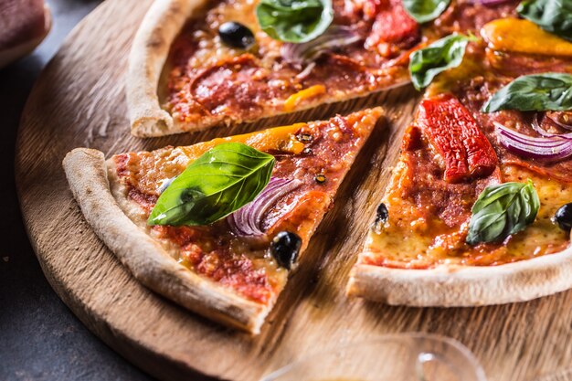 Pizza diavolo tradycyjny włoski posiłek z pikantnym salami peperoni chili, cebulowymi oliwkami i bazylią.