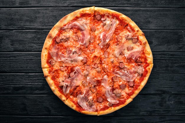 Pizza Lardon. Boczek, pomidorki koktajlowe, salami z kiełbasą. Na drewnianym tle. Widok z góry.