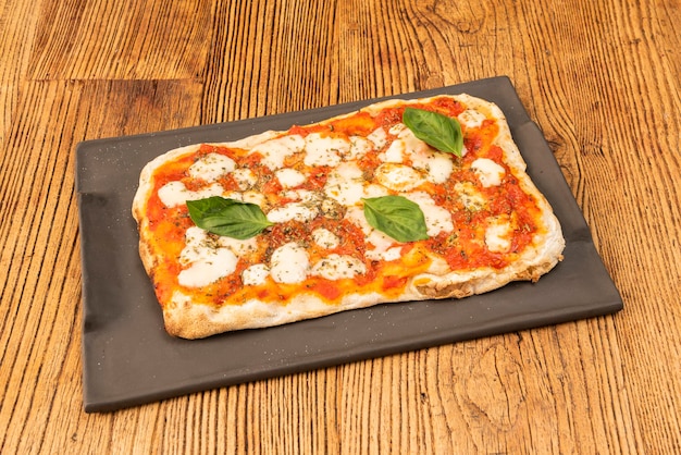 Zdjęcie pizza margarita z serem mozzarella bufala w prostokątnym formacie z bazylią i pomidorem oraz ciastem z mąki pszennej