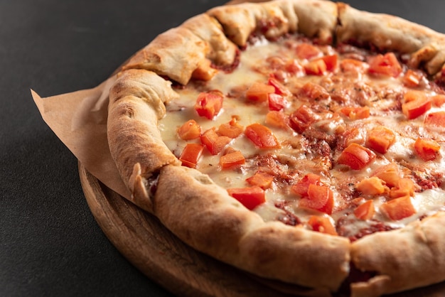 Pizza neapolitańska z przyprawami, pomidorami i serem mozzarella na ciemnym tle pizza margarita dowcip
