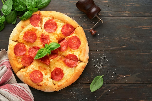 Pizza Pepperoni Tradycyjna pizza pepperoni i składniki do gotowania pomidory, bazylia na tle drewnianego stołu Tradycyjne włoskie jedzenie Widok z góry Makieta