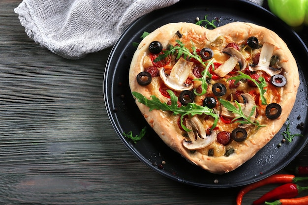 Pizza w kształcie serca na metalowej tacy na drewnianym tle