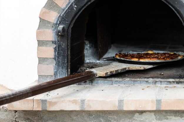 Pizza wykonana w piecu z drewna rzemieślniczego pomalowanego na biało, zbudowanym na zewnątrz, tło