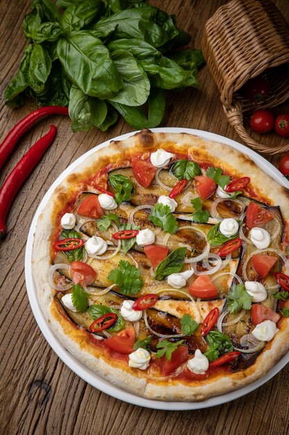 pizza z bakłażanem, serem, pomidorami i papryczką chili w restauracji