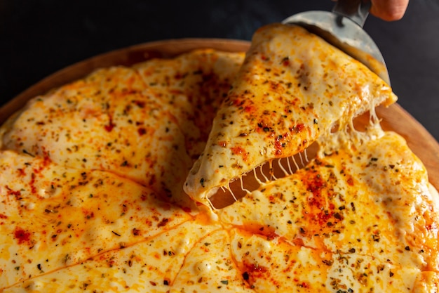 Pizza z dużą ilością roztopionego sera na ciemnym tle Włoska pizza