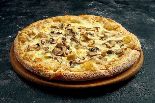 Pizza z kremowym sosem, pieczarkami i serem na czarnym kamiennym tle. Kąt widzenia 45 stopni. Zbliżenie, selektywne skupienie