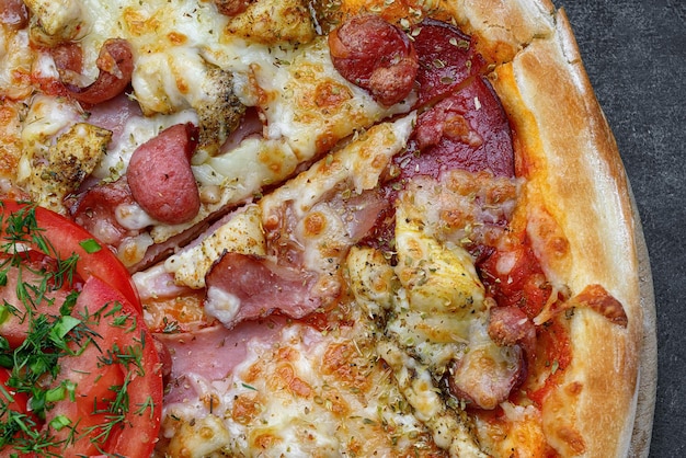 Pizza z mięsem kiełbasianym, serem z kurczaka i pomidorami na szarym betonowym tle z selektywną ostrością Poziomo