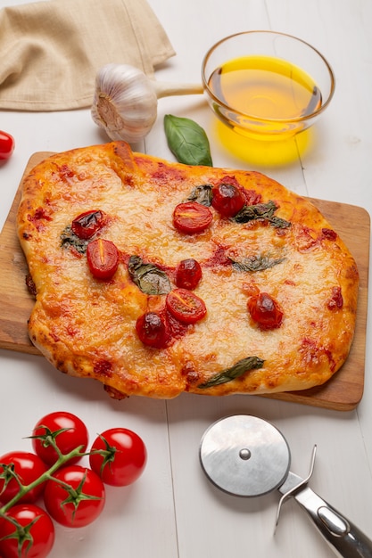 Pizza z mozzarellą, połową pomidorów cherry, przyprawami i świeżą bazylią