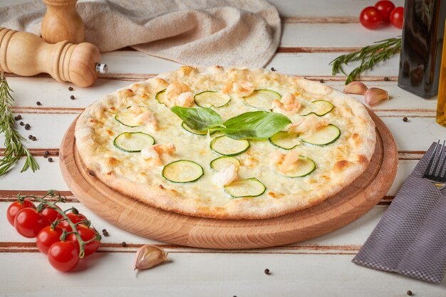 Pizza z plastrami, sosem i ziołami, drewniana biała