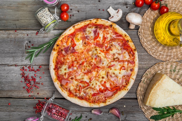 Pizza z pomidorami, mozzarellą, czarnymi oliwkami i bazylią. Wyśmienicie włoska pizza na drewnianej pizzy desce. Widok z góry stołu