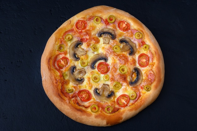 Pizza z pomidorami mozzarella pieczarkami salami na czarnym tle