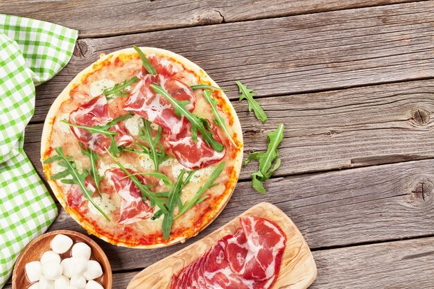 Pizza z prosciutto i mozzarellą na drewnianym stole