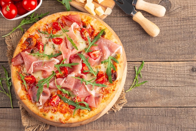Zdjęcie pizza z prosciutto, szynką, arugulą, pomidorami, serem pesto i parmesanem, kuchnia włoska