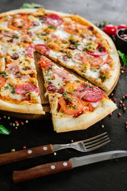 Pizza z salami i szynką na czarnym tle