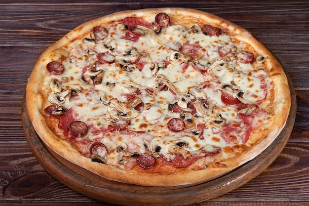 Pizza z serem i ziołami na drewnianym talerzu z serem i pomidorkami cherry.