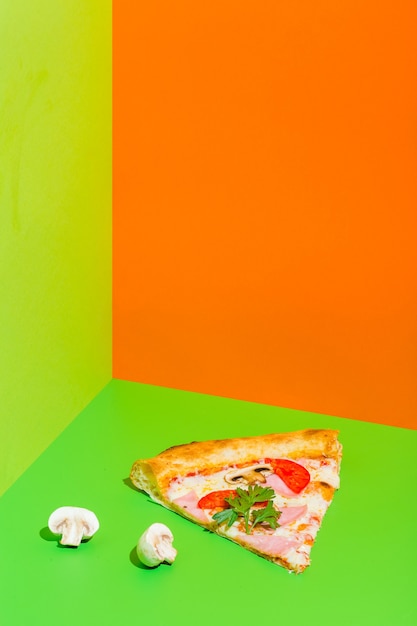 Pizza z szynką i pieczarkami na papierowym zielonym i pomarańczowym tle wysokiej jakości zdjęcie
