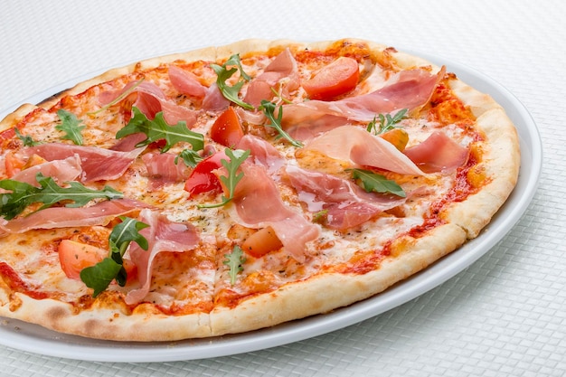 Pizza z szynką prosciutto i rukolą Na białym tle