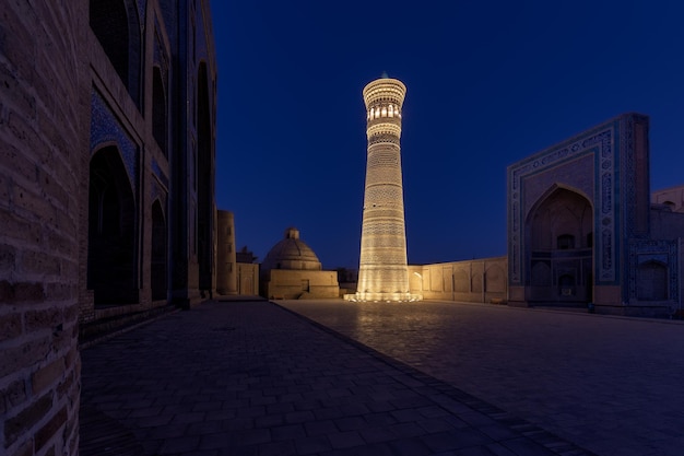 Plac PoiKalyan w nocy z jasno oświetlonym minaretem Kalyan Buchara Uzbekistan