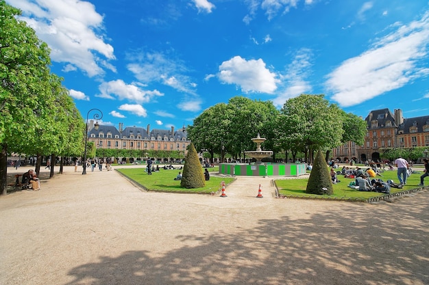 Place des Vosges i piękny park oraz ludzie siedzący na trawniku w centrum Paryża we Francji.