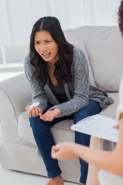 Płacząca kobieta mówi do swojego terapeuty, który robi notatki